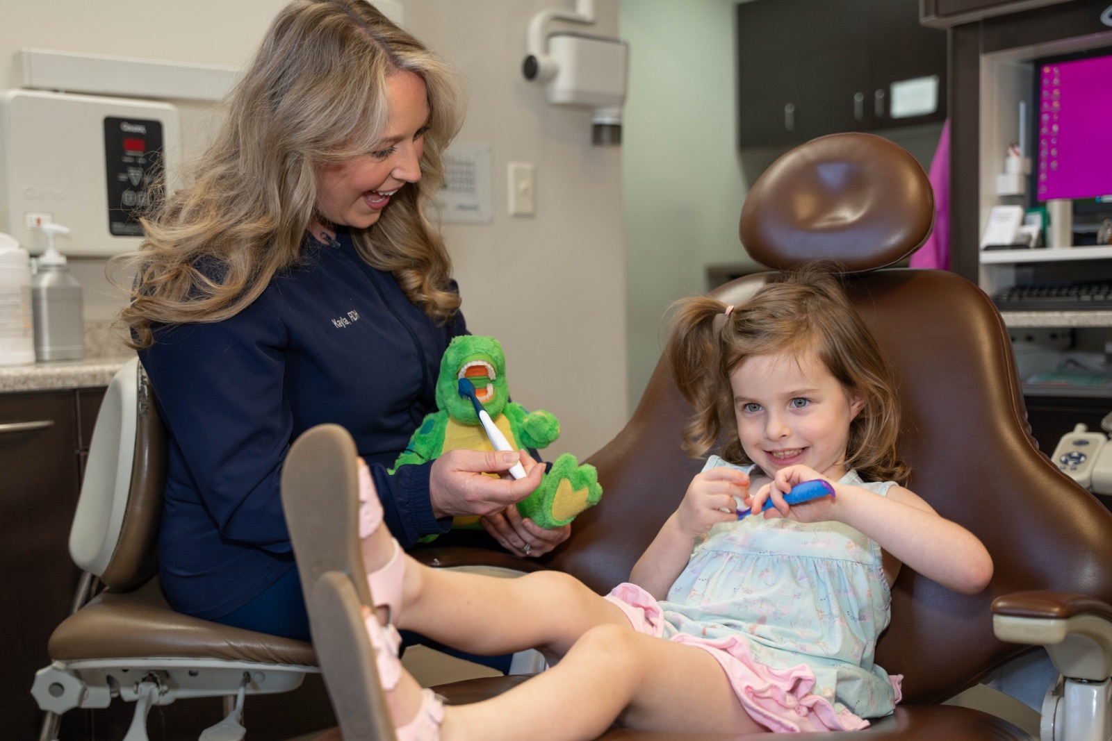 A dental assistant with a child brushing teeth